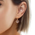A woman wearing a pair of Blue Evil Eye Zirconia stones Dangle huggies Earrings Rose gold filled with a diamond in the middle.
